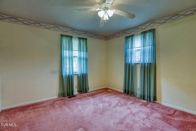 carpeted spare room with a wealth of natural light and ceiling fan