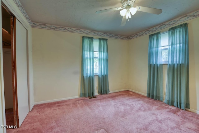 empty room featuring ceiling fan, a healthy amount of sunlight, and light carpet