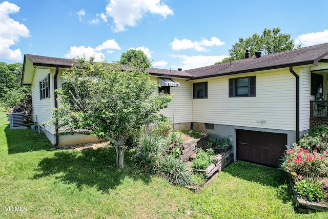 rear view of house with a garage, central AC unit, and a lawn