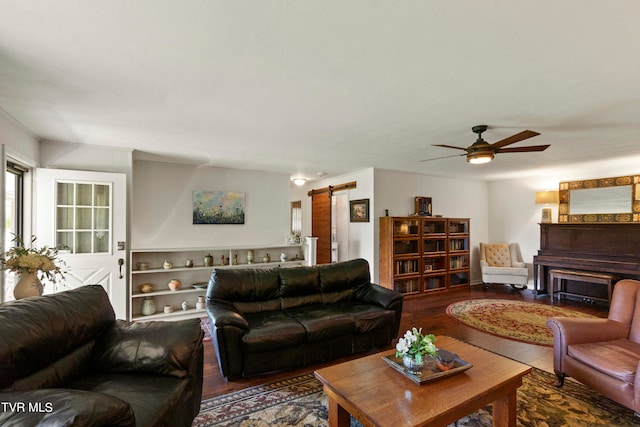 living room featuring a barn door, ceiling fan, and wood-type flooring