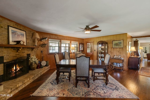 dining room featuring a fireplace, wood walls, and dark wood-type flooring