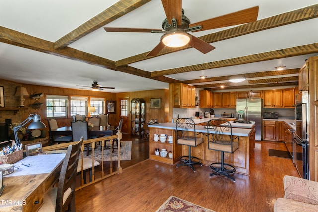 interior space featuring ceiling fan, beam ceiling, wood walls, and wood-type flooring