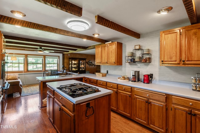 kitchen with beam ceiling, wood-type flooring, ceiling fan, and stainless steel gas cooktop