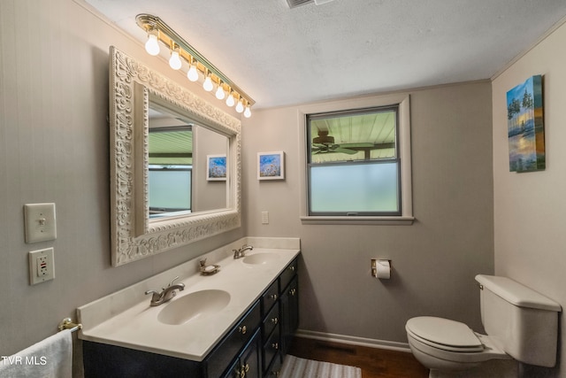 bathroom with vanity with extensive cabinet space, toilet, hardwood / wood-style flooring, double sink, and a textured ceiling