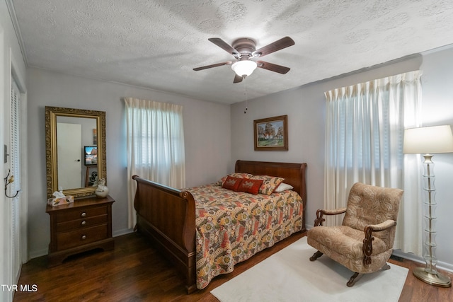 bedroom with a textured ceiling, dark hardwood / wood-style floors, and ceiling fan