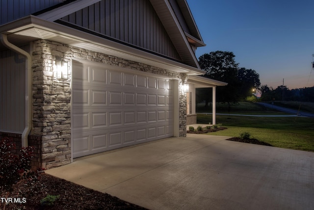 garage at dusk featuring a lawn