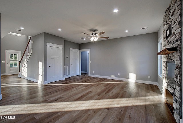 unfurnished living room with ceiling fan, light wood-type flooring, and a fireplace