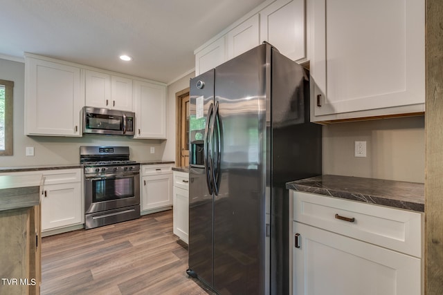 kitchen with appliances with stainless steel finishes, crown molding, hardwood / wood-style flooring, and white cabinets