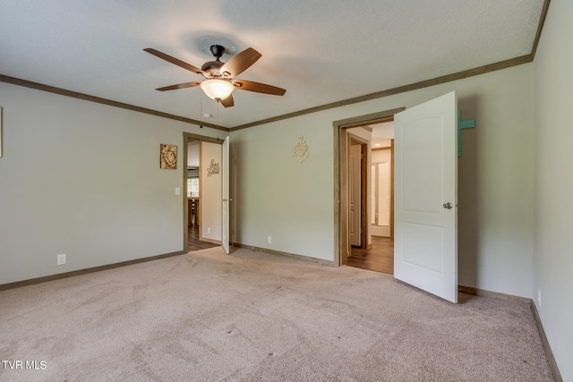 carpeted spare room with ceiling fan and crown molding