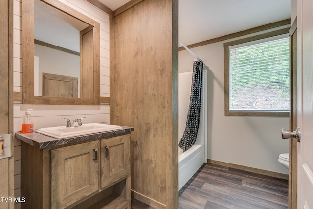 full bathroom with crown molding, hardwood / wood-style flooring, shower / bath combination with curtain, large vanity, and toilet