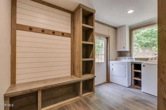 laundry room with a wealth of natural light, washer and clothes dryer, cabinets, and hardwood / wood-style flooring