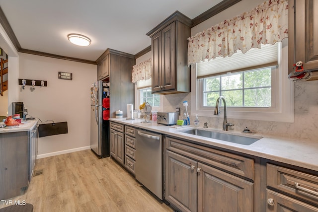 kitchen with stainless steel appliances, light hardwood / wood-style flooring, crown molding, and sink