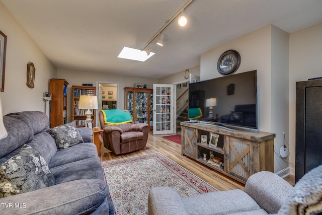 living room featuring hardwood / wood-style flooring, a textured ceiling, a skylight, and rail lighting