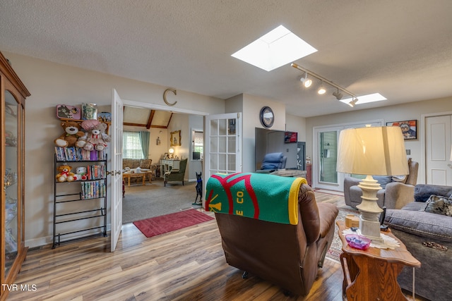 living room featuring rail lighting, hardwood / wood-style flooring, a textured ceiling, and a skylight