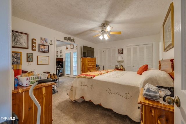 bedroom with two closets, ceiling fan, carpet floors, and a textured ceiling