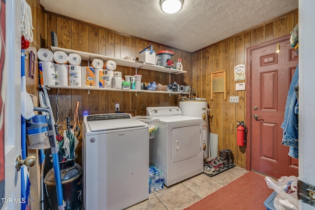 washroom featuring independent washer and dryer, a textured ceiling, water heater, light tile floors, and wood walls