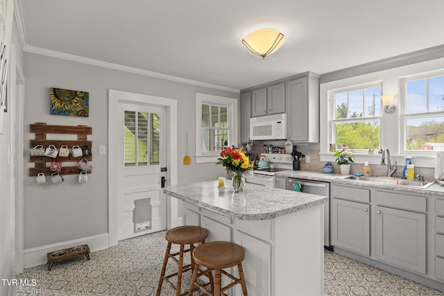 kitchen featuring crown molding, white appliances, light tile flooring, a kitchen island, and sink