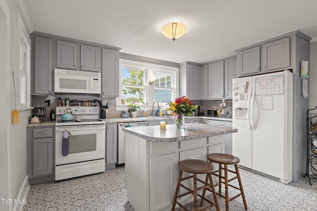 kitchen featuring a kitchen island, white appliances, a breakfast bar area, tasteful backsplash, and light tile flooring