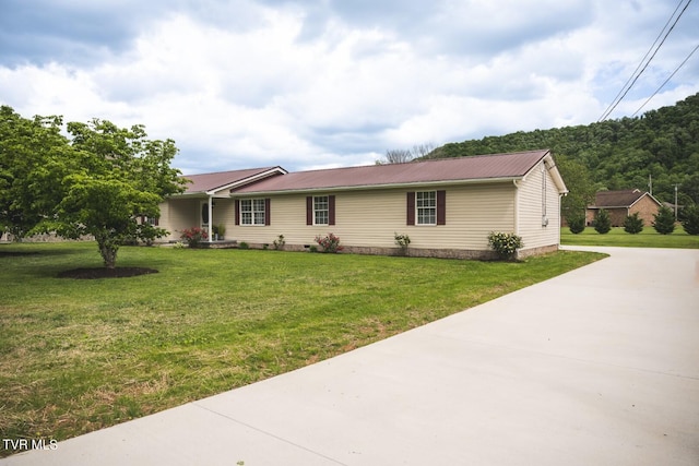 ranch-style house with crawl space, metal roof, concrete driveway, and a front lawn