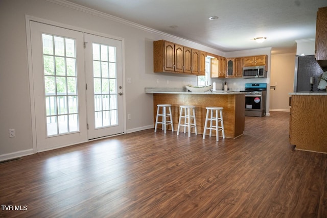 1466 Broad St, Elizabethton, TN 37643 - kitchen featuring ornamental molding, dark wood-style floors, stainless steel appliances, a peninsula, and brown cabinetry