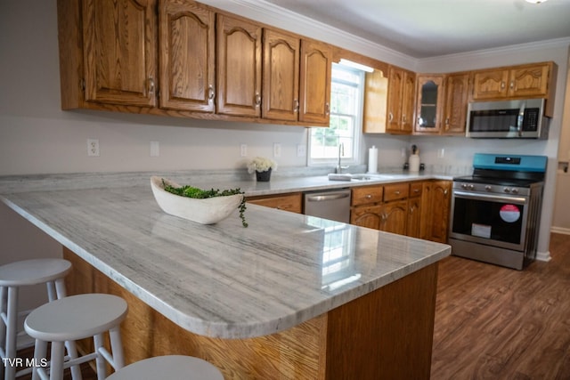 1466 Broad St, Elizabethton, TN 37643 - kitchen featuring a breakfast bar area, a peninsula, a sink, appliances with stainless steel finishes, and brown cabinets