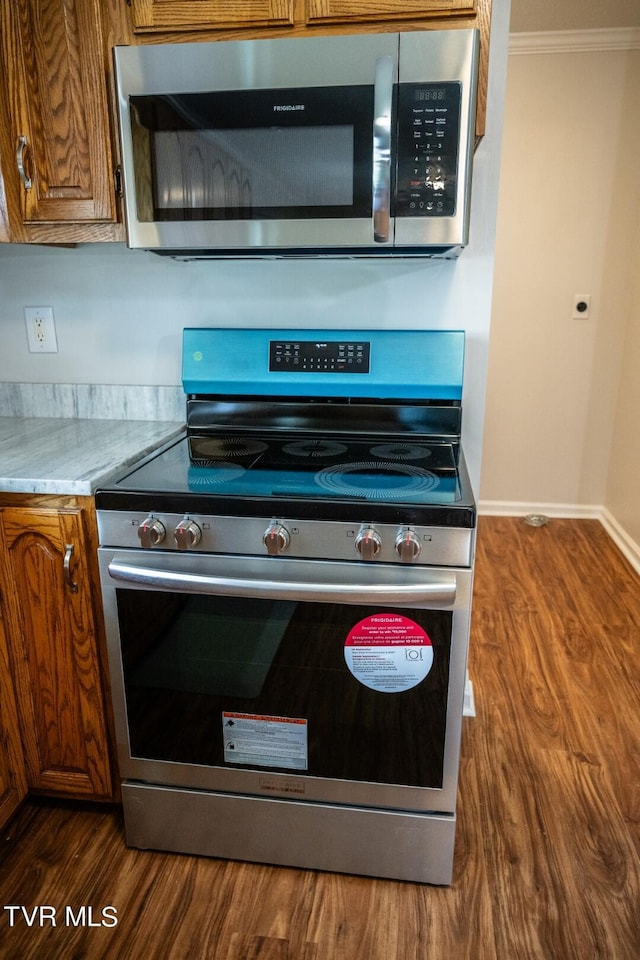 1466 Broad St, Elizabethton, TN 37643 - kitchen featuring baseboards, ornamental molding, brown cabinets, appliances with stainless steel finishes, and dark wood-style flooring