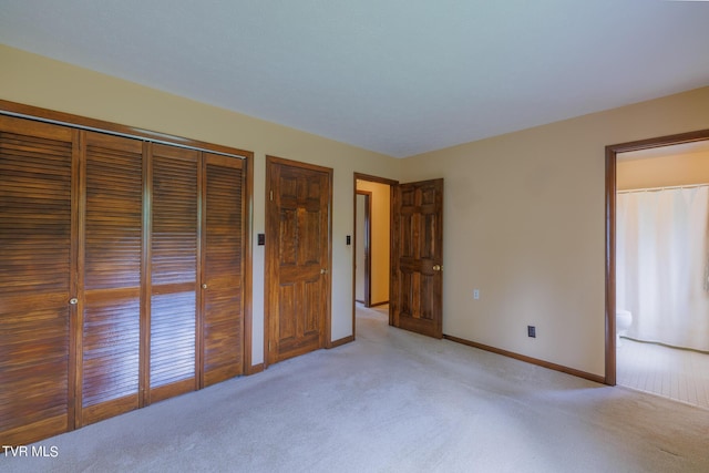 unfurnished bedroom with light carpet, ensuite bath, and a closet
