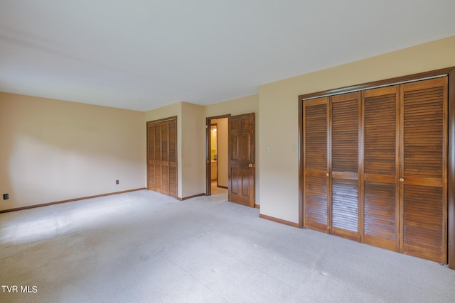 unfurnished bedroom with light colored carpet and two closets