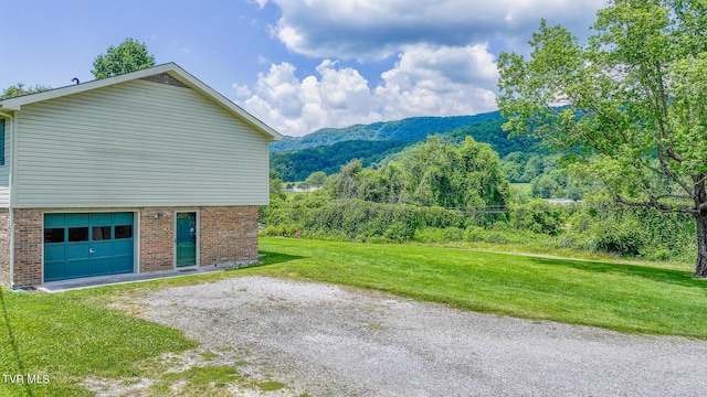 view of side of property with a garage, a mountain view, and a yard