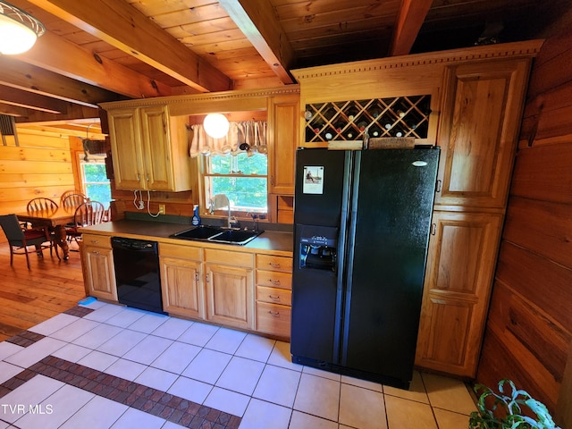 kitchen featuring wooden walls, sink, light tile patterned floors, black appliances, and beam ceiling