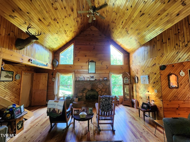 living room with wooden walls, high vaulted ceiling, wooden ceiling, and light wood-type flooring