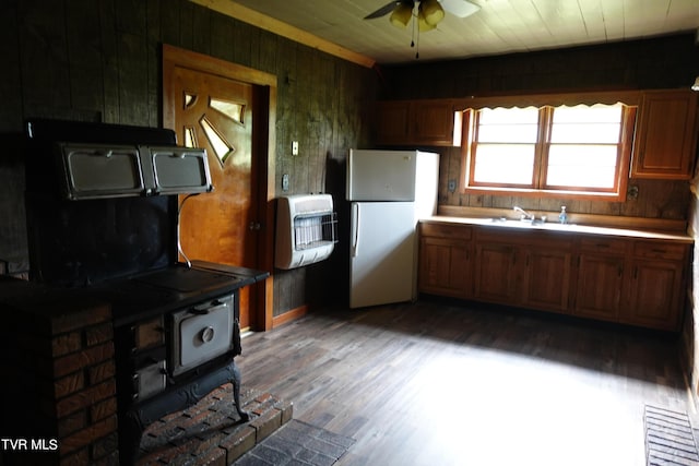 kitchen with white refrigerator, wood ceiling, heating unit, and a wood stove