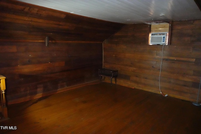 basement featuring wooden walls, dark hardwood / wood-style flooring, and a wall unit AC