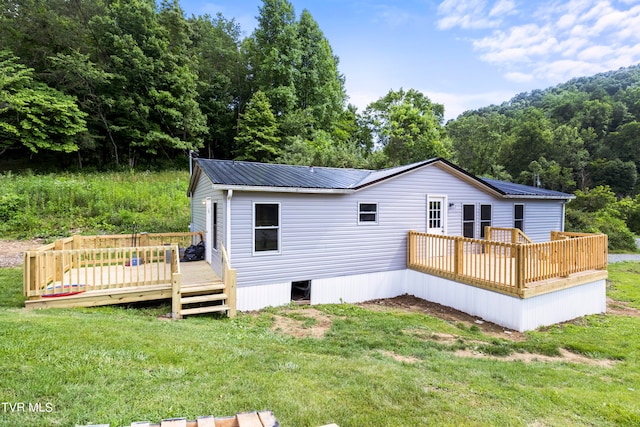 rear view of house featuring a deck and a yard