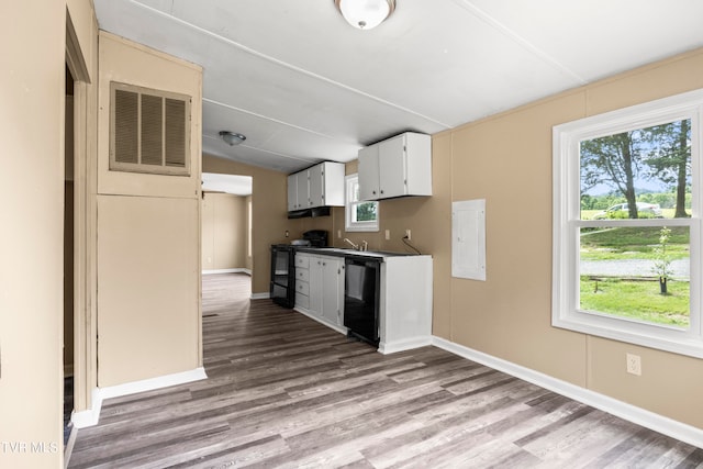 kitchen featuring a healthy amount of sunlight, white cabinets, black appliances, and hardwood / wood-style flooring