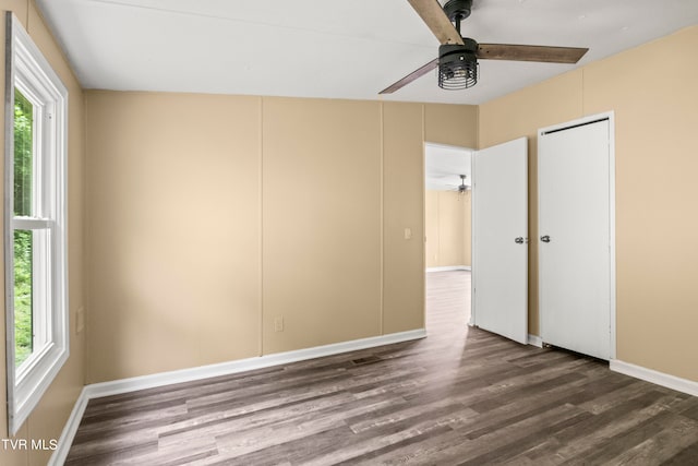 empty room with dark hardwood / wood-style flooring, ceiling fan, and plenty of natural light