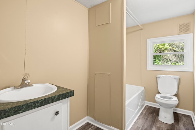 bathroom with a textured ceiling, wood-type flooring, vanity, and toilet