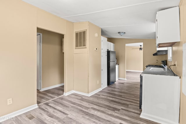 kitchen with sink, wood-type flooring, ceiling fan, and black refrigerator