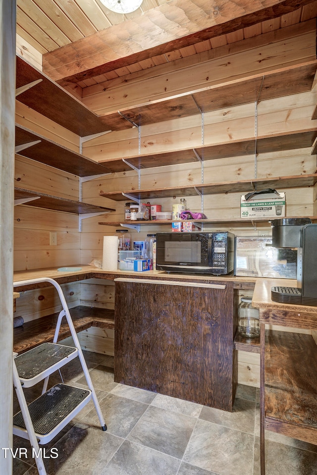 interior space with hanging light fixtures, wood ceiling, and wood walls