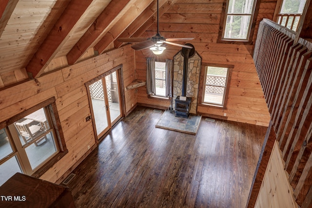 bonus room featuring wood walls, lofted ceiling with beams, a wood stove, and dark hardwood / wood-style flooring