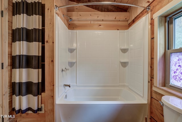 bathroom with toilet, wood walls, and shower / tub combo with curtain