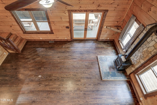 unfurnished living room featuring a healthy amount of sunlight, a wood stove, and dark hardwood / wood-style floors