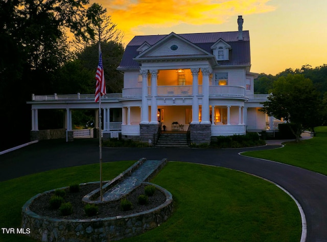 neoclassical / greek revival house featuring covered porch, a balcony, and a lawn