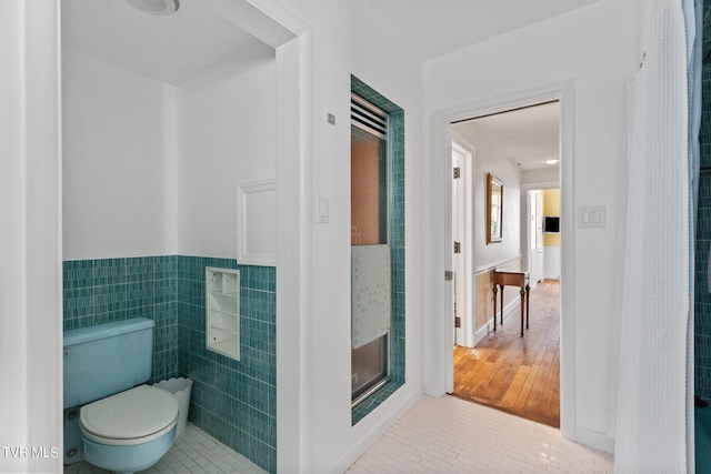 bathroom with tile walls, toilet, and tile floors