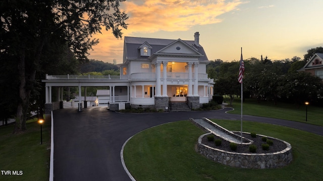 neoclassical / greek revival house featuring a carport, a yard, a balcony, and central AC unit