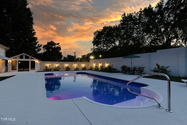 pool at dusk featuring a patio