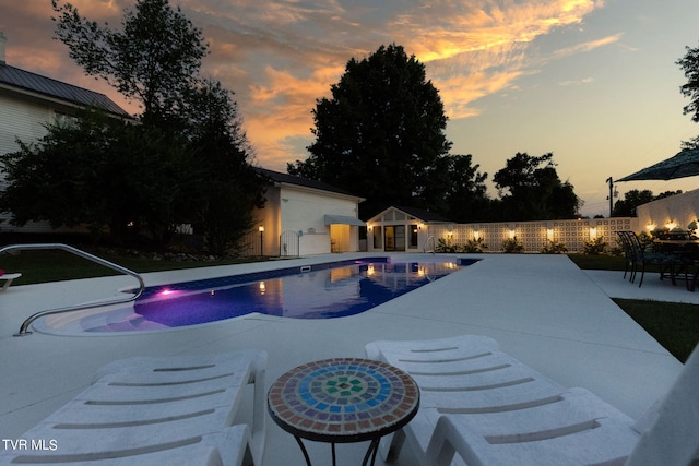 pool at dusk featuring a patio area and an outdoor structure