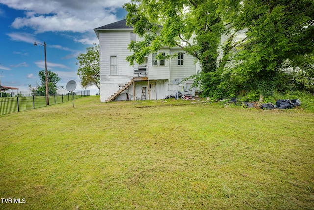 back of house with fence, a lawn, and stairs