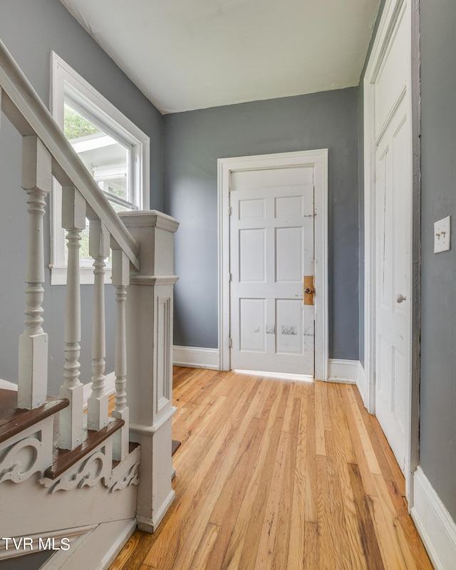 entrance foyer featuring stairs, light wood-style floors, and baseboards