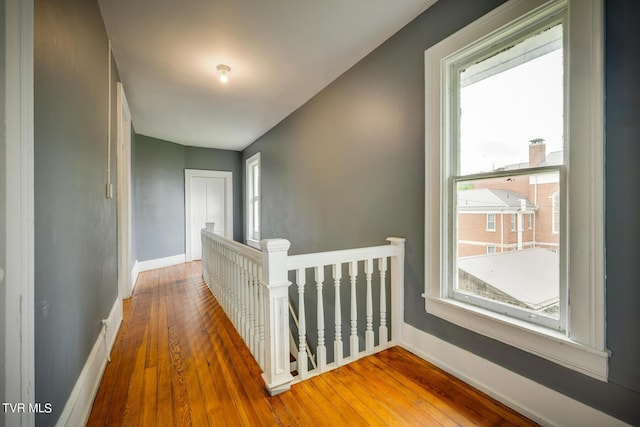 hallway with plenty of natural light, an upstairs landing, baseboards, and wood-type flooring